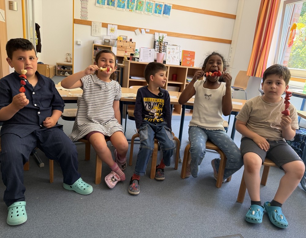 Auf dem Bild sind Schülerinnen und Schüler mit ihren fertigen Obstspießen zu sehen.